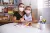 Uma menina e sua mãe estão sentadas a uma mesa na escola. As duas usam máscara.