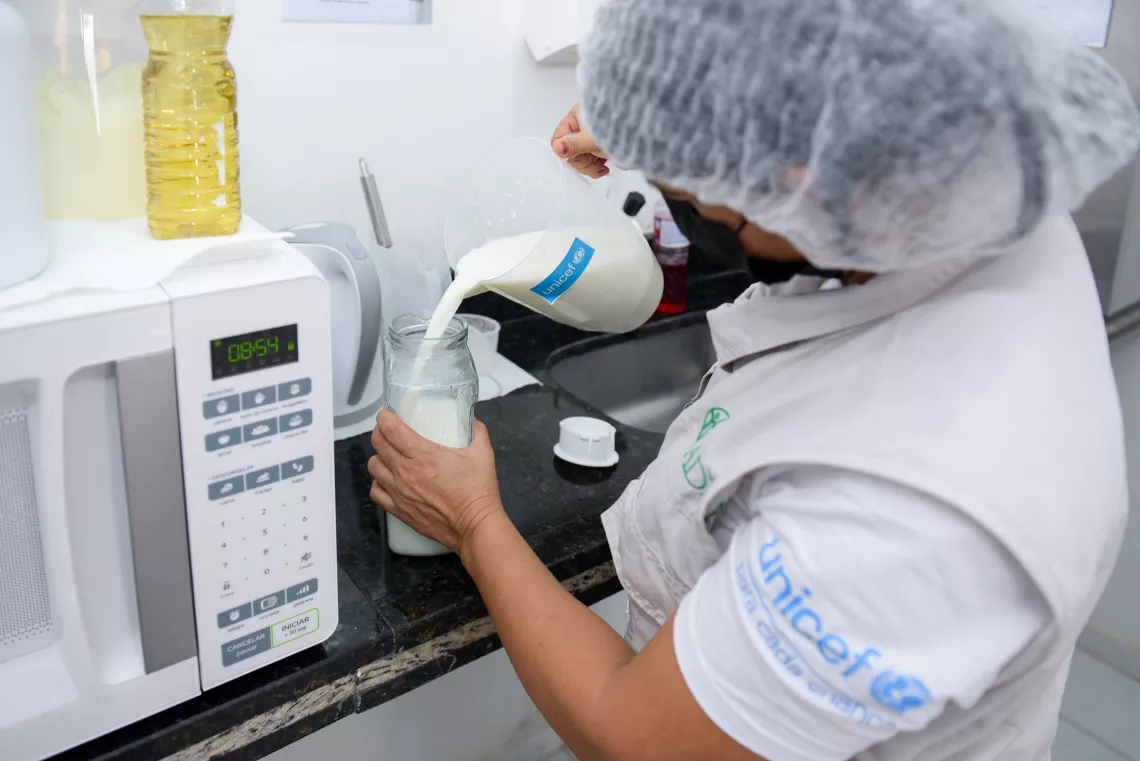 Profissional de sa&uacute;de serve um copo de leite em um  balc&atilde;o de cozinha.