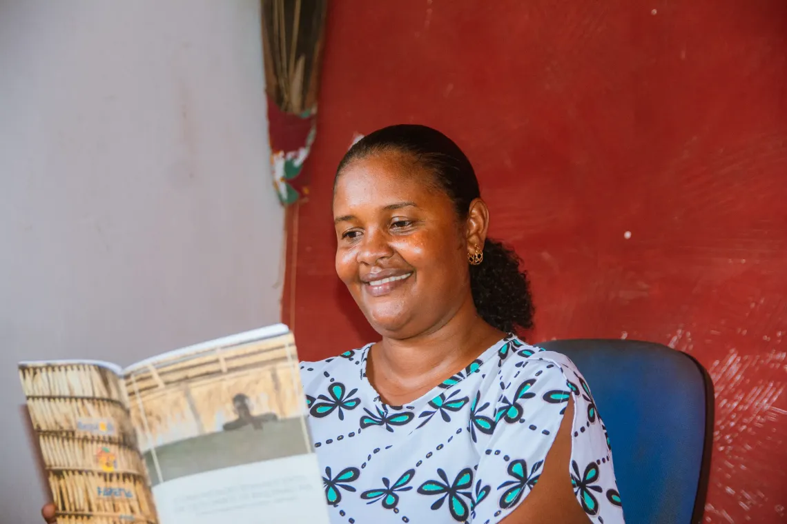 mulher sorri enquanto l&ecirc; livro