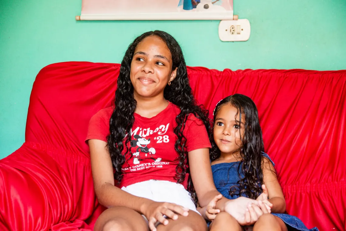 duas meninas sentadas em sof&aacute; verelho