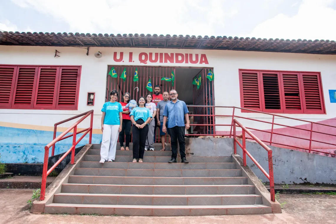grupo de pessoas em escadarias em frente um pr&eacute;dio
