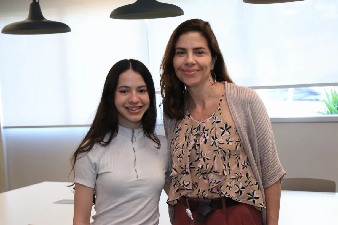 mulher e menina posam para foto em uma sala de reuni&otilde;es
