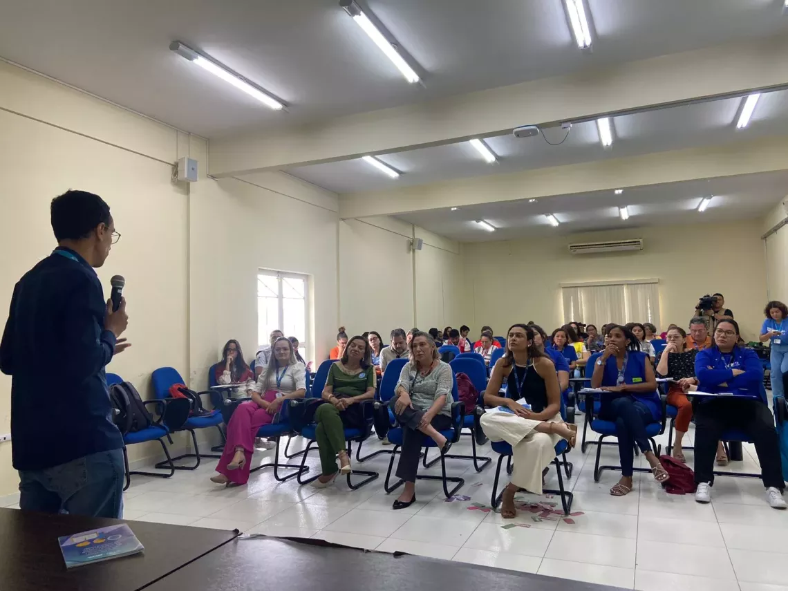 Homem ministra palestra para pessoas em audit&oacute;rio