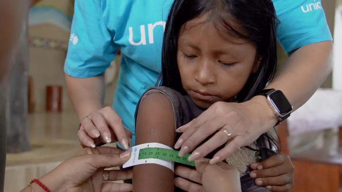 Profissional do UNICEF apoia profissional de sa&uacute;de para medir circunfer&ecirc;ncia braquial em uma menina ind&iacute;gena.
