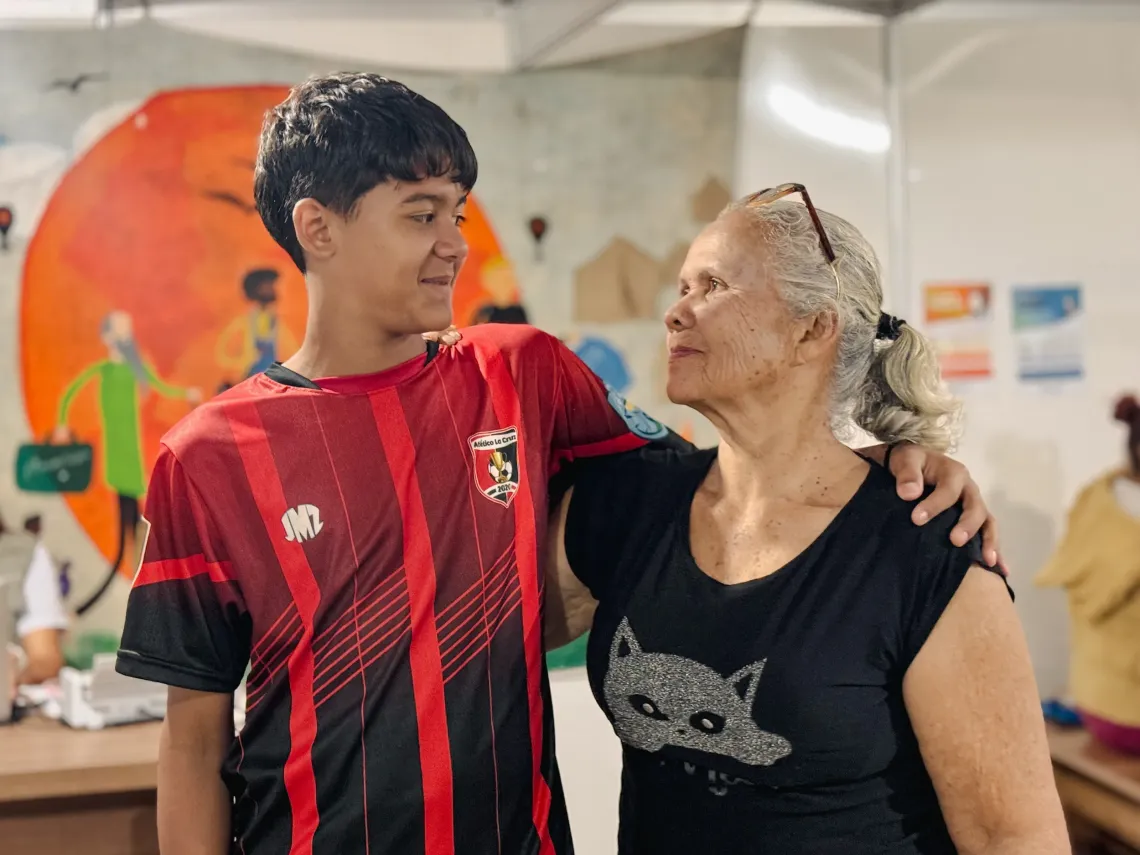 jovem vestindo camiseta esportiva vermelha abra&ccedil;a mulher de cabelos brancos