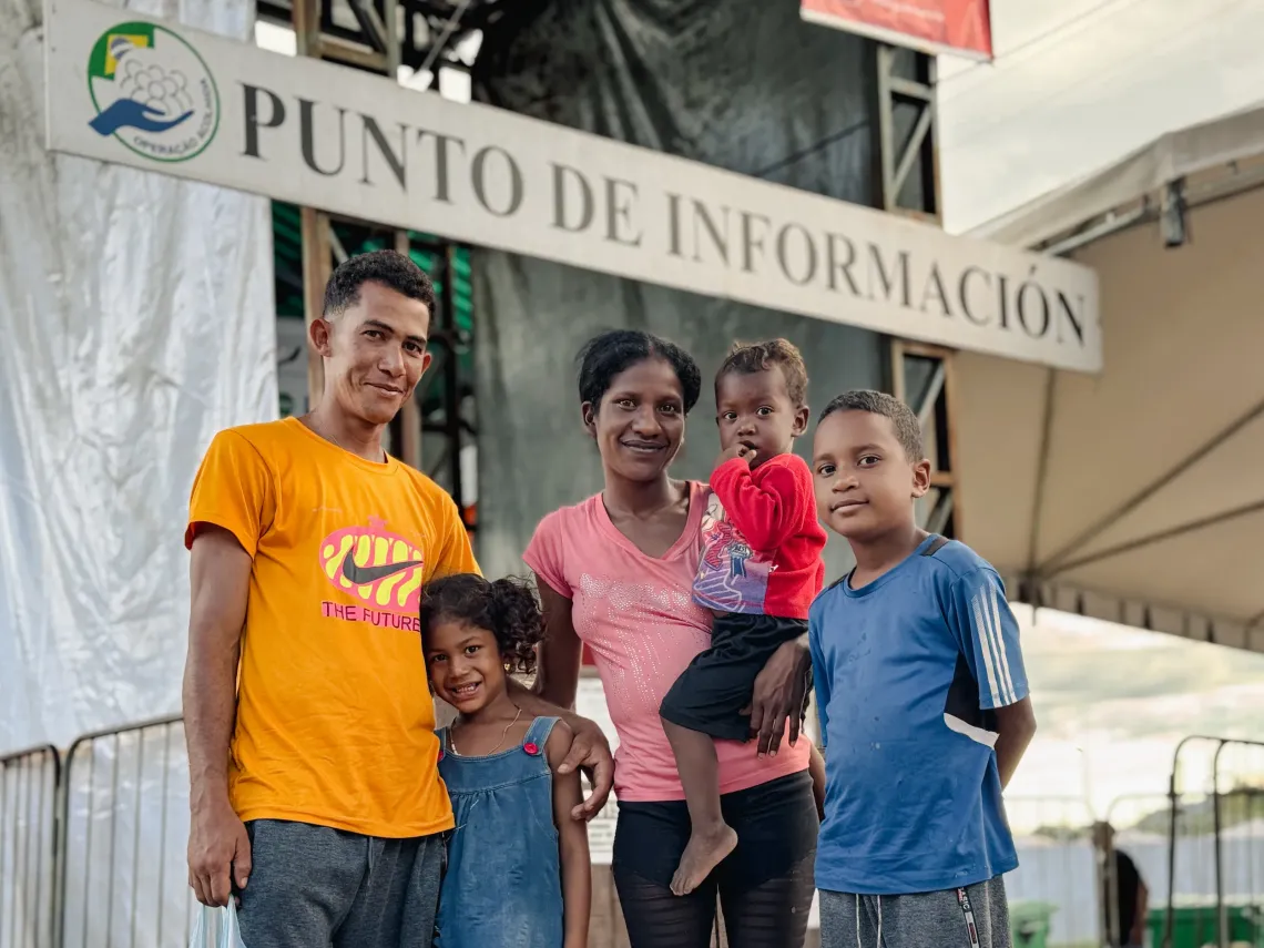 fam&iacute;lia de 5 pessoas posa para foto em frente a um Punto de Informacion