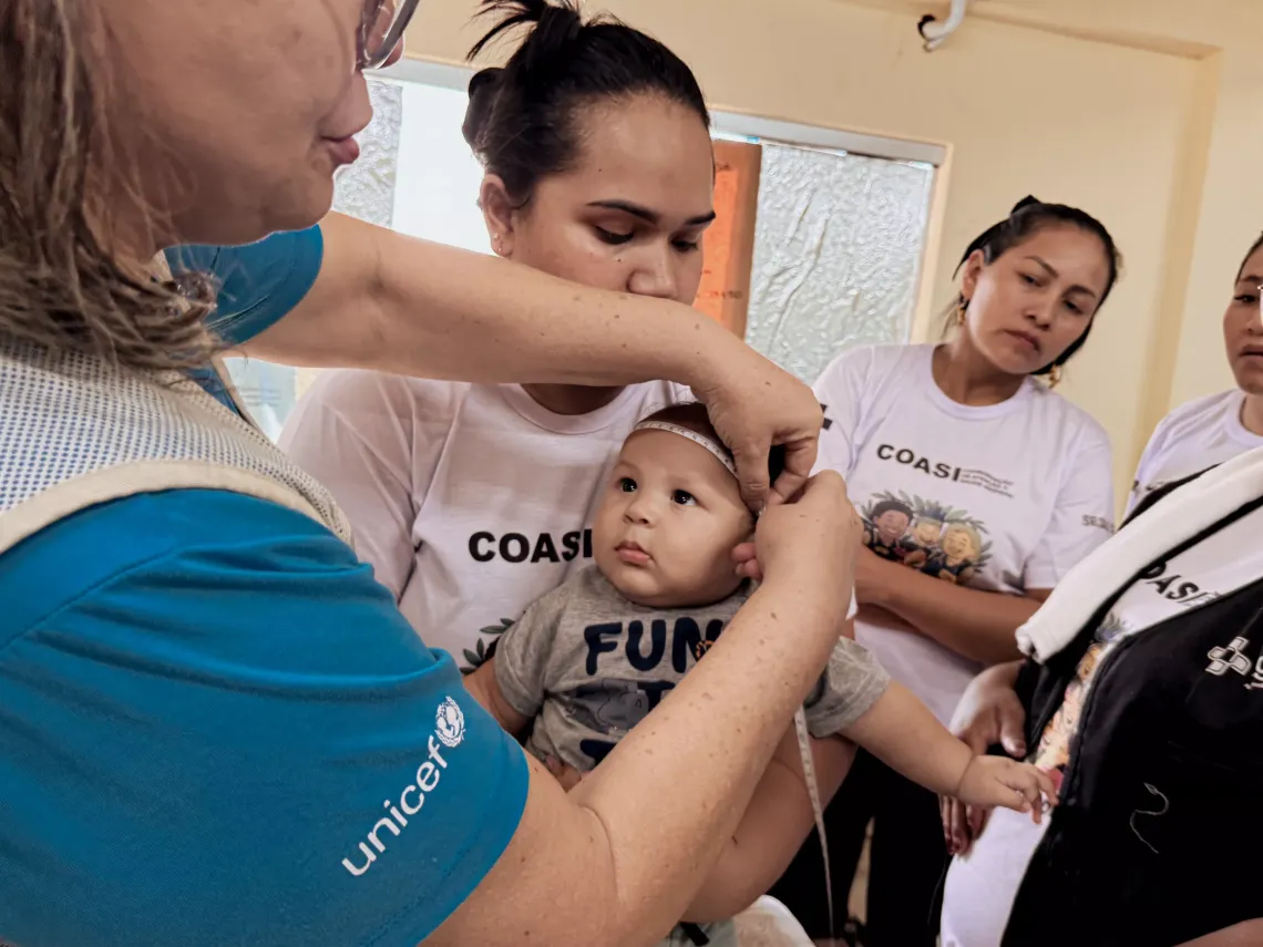 funcion&aacute;ria do UNICEF mede circunfer&ecirc;ncia de cabe&ccedil;a de beb&ecirc;, que est&aacute; no colo da m&atilde;e