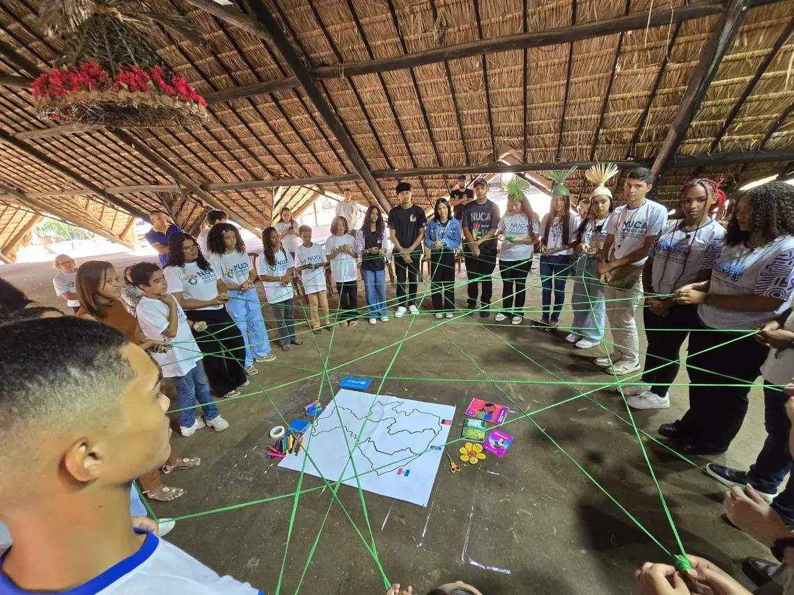 adolescentes participam de atividade usando cord&otilde;es verdes em c&iacute;rculo 