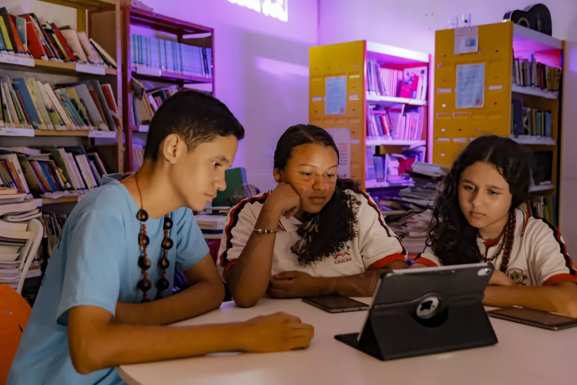 tr&ecirc;s jovens v&ecirc;em conte&uacute;do no computador