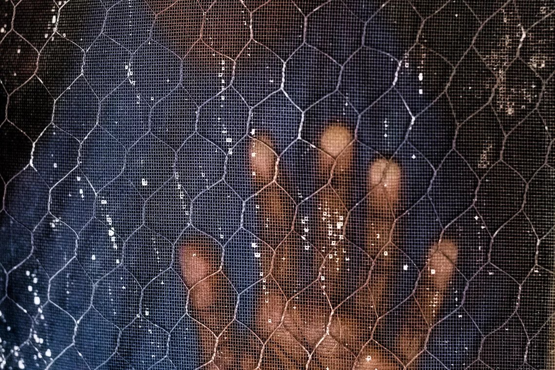 Foto mostra uma m&atilde;o pressionada em uma tela de prote&ccedil;&atilde;o.