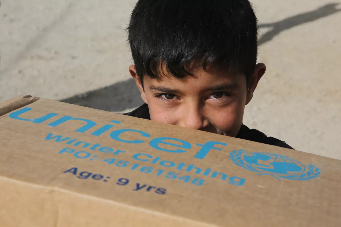 Foto mostra um menino segurando uma caixa de papel&atilde;o com o logo do UNICEF.