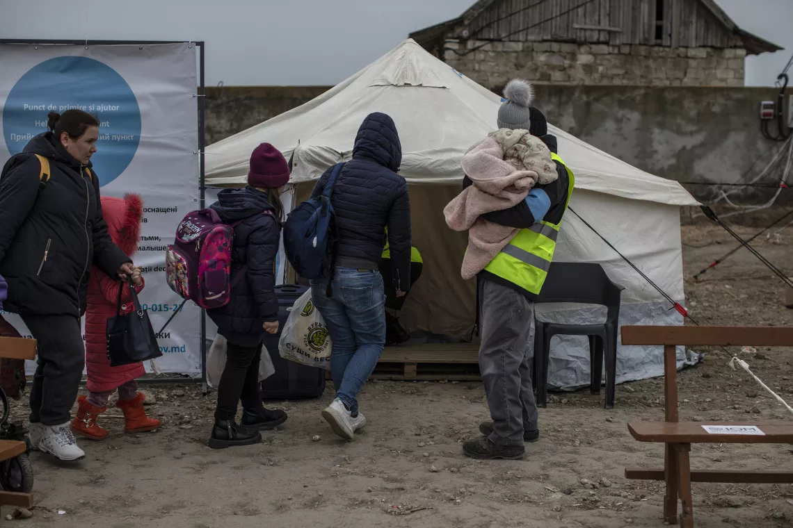 Foto mostra algumas pessoas, entre elas crian&ccedil;as e adolescentes, entrando em uma tenda. 