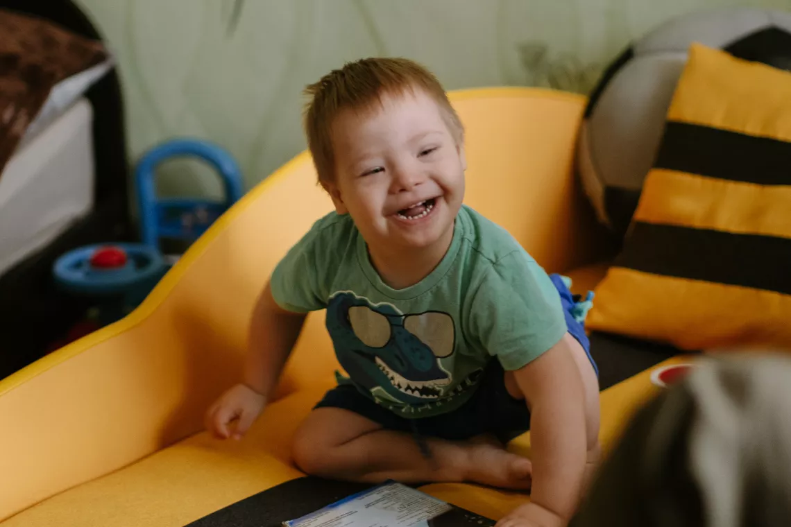 Foto mostra um beb&ecirc; sentado em um sof&aacute; e sorrindo
