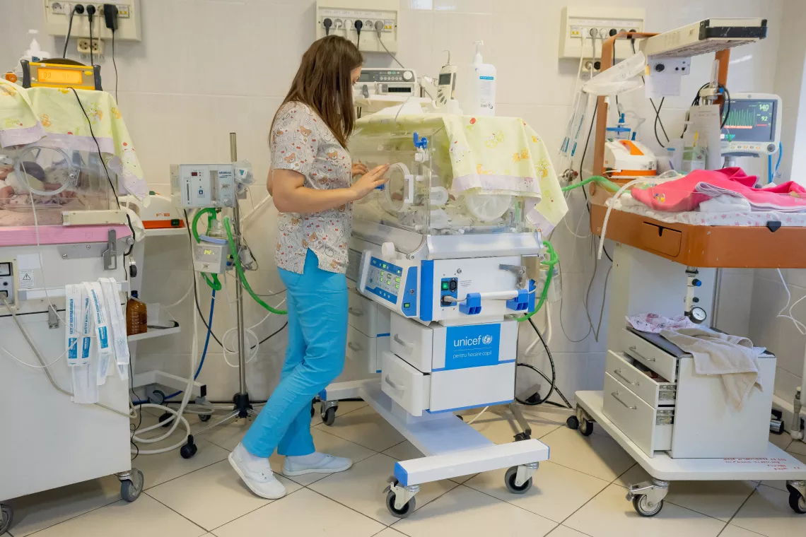Foto mostra uma profissional de sa&uacute;de mexendo em uma incubadora.