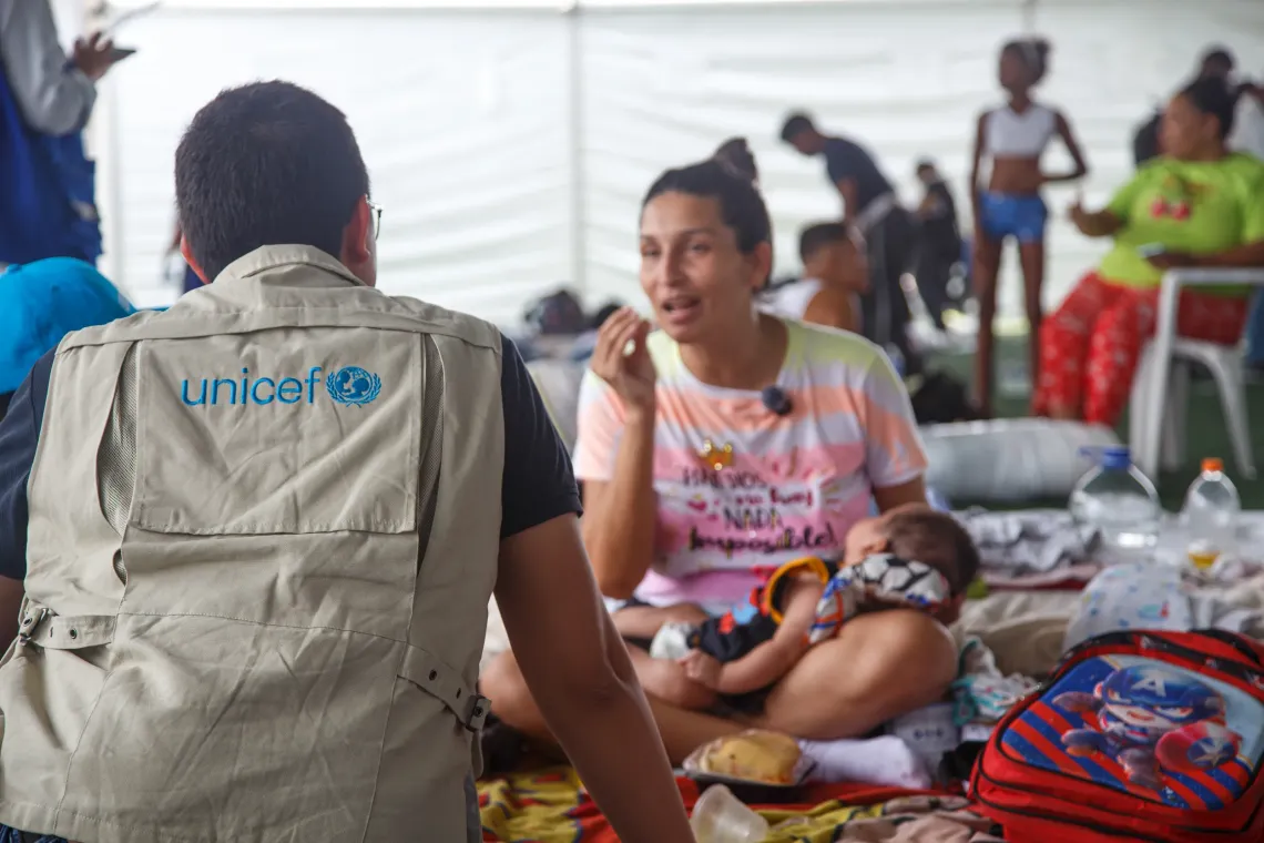 mulher com beb&ecirc; no colo conversa com funcion&aacute;rio do UNICEF 