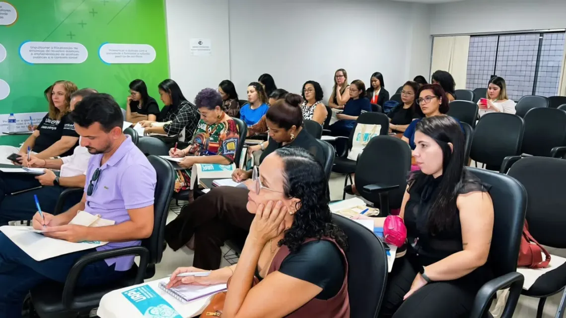 grupo de pessoas participa de treinamento sentados em uma sala que parece sala de aula