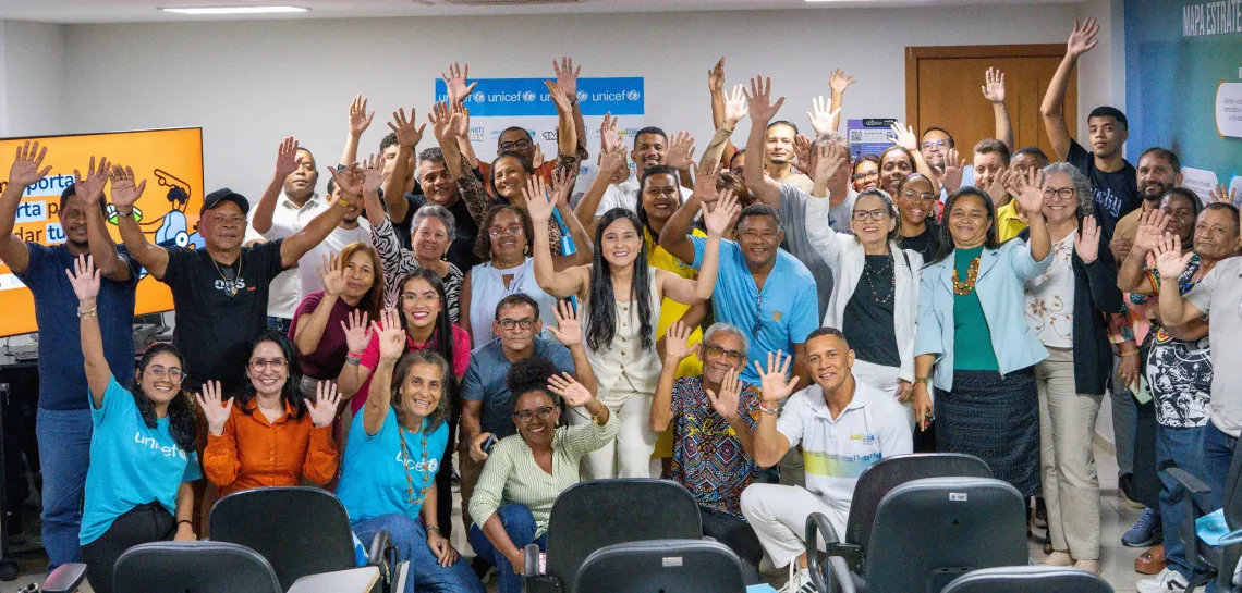 grupo de pessoas sorri com as m&atilde;os para cima