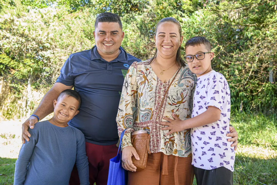 Pai, m&atilde;e e dois filhos sorriem para a foto.