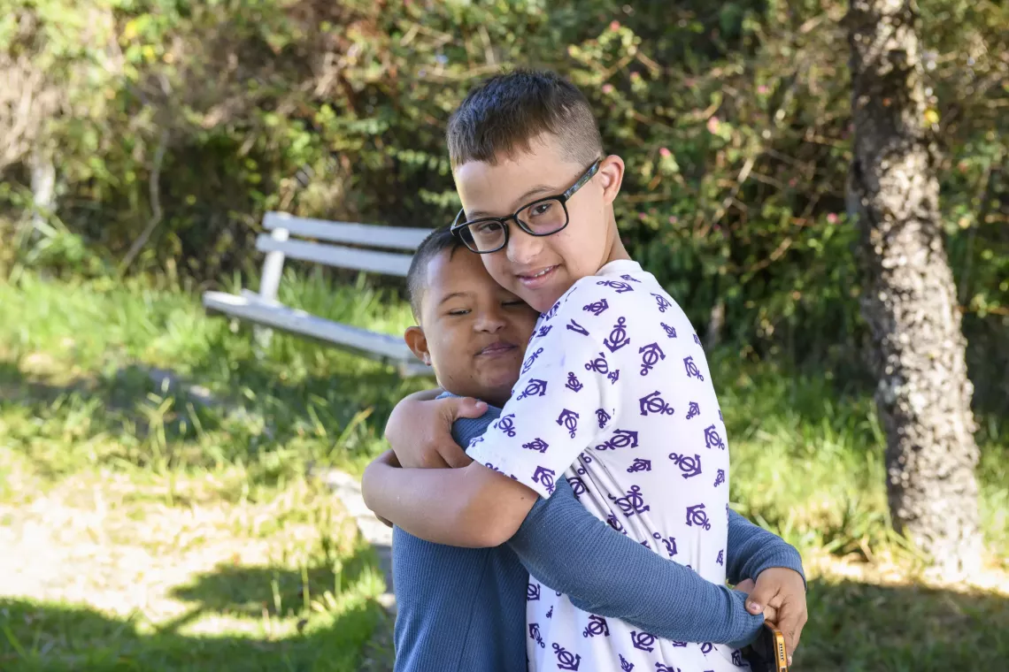 Dois meninos se abra&ccedil;am e olham para a foto