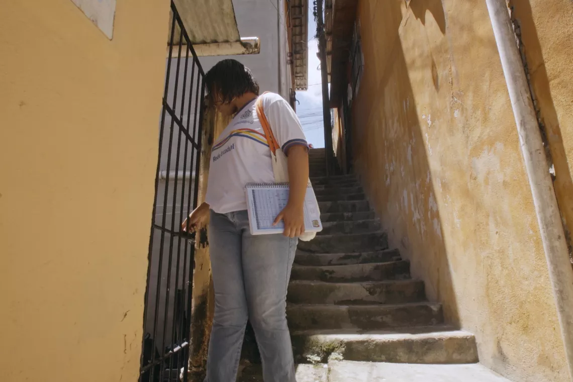 Foto mostra uma adolescente saindo de casa ao lado de uma escadaria