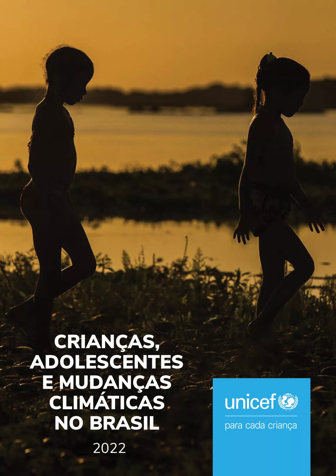 Foto mostra duas crian&ccedil;as de perfil andando nas margens de uma lagoa. Elas est&atilde;o contra a luz, no p&ocirc;r-do-sol.