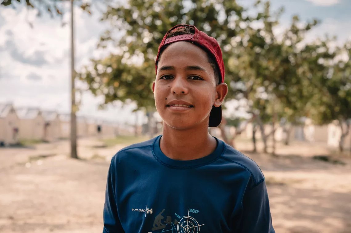 Foto mostra um adolescente em um espa&ccedil;o ao ar livre. Ele est&aacute; olhando para a c&acirc;mera.