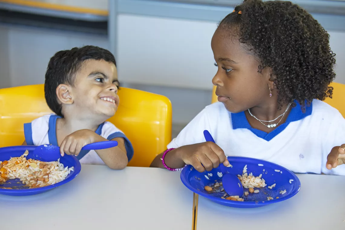Foto mostra duas crian&ccedil;as no refeit&oacute;rio de uma escola