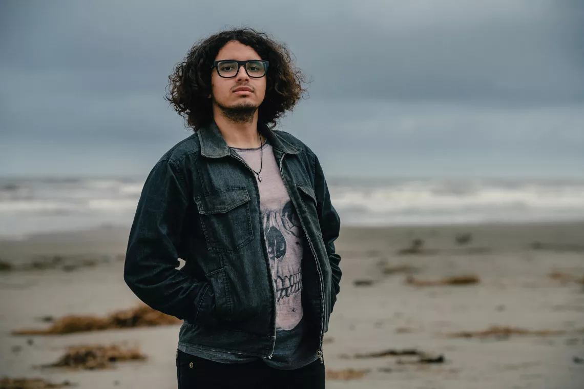 foto mostra um jovem em p&eacute; em cima de um terreno na beira do mar