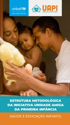 Foto mostra uma mulher segurando uma beb&ecirc; e um homem mostrando um bichinho de pel&uacute;cia para essa beb&ecirc;