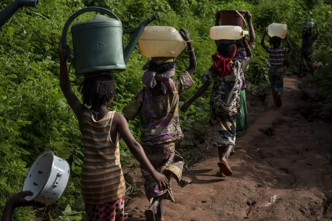 meninas em fila com vasilhas d'&aacute;gua na cabe&ccedil;a andam por uma trilha na floresta na Rep&uacute;blica Centro-Africana
