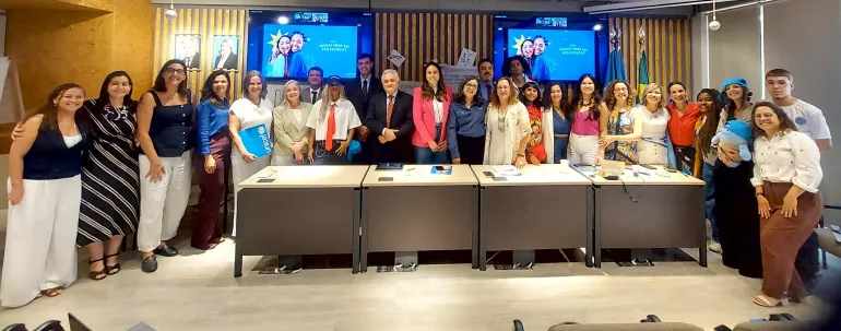 grupo de pessoas posa para foto em audit&oacute;rio