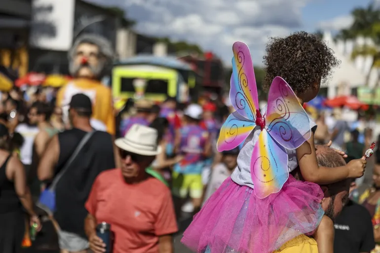 crian&ccedil;a no ombro de um adulto durante um carnaval