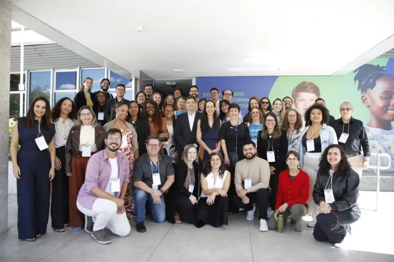 grupo de pessoas posa para foto em frente a pr&eacute;dio p&uacute;blico