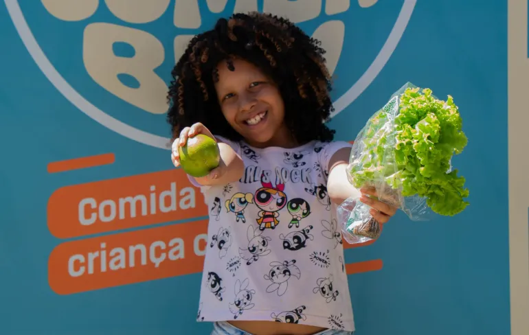 menina segura fruta e p&eacute; de alface