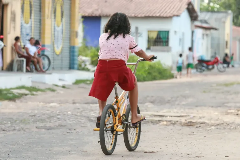 menina de costas andando de bicicleta em uma rua