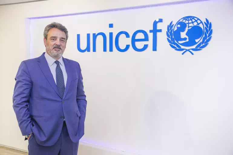 homem de terno azulem frente a uma logomarca do UNICEF