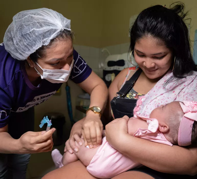 Profissional de Sa&uacute;de aplica vacina em bebe no colo da m&atilde;e