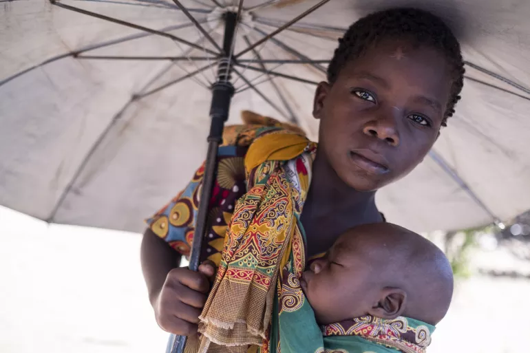 Aruminda Luis segura seu irm&atilde;o, Antonio, em um acampamento montado para pessoas deslocadas no Centro Testemunhas de Jeov&aacute;, em Dondo, Mo&ccedil;ambique. O ciclone Idai deslocou milhares de pessoas.