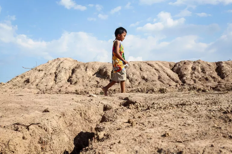 menino no centro da foto em uma &aacute;rea desertificada