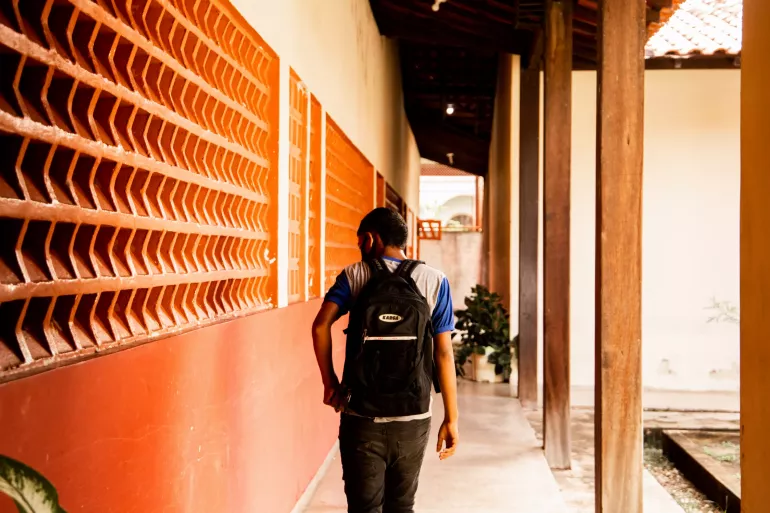 Jovem estudante de costas, com mochila nas costas
