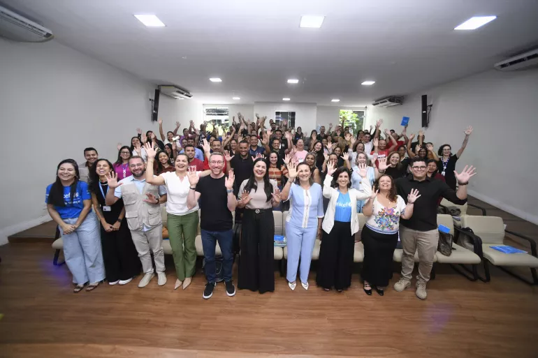 grupo de pessoas posa para foto em plateia de audit&oacute;rio