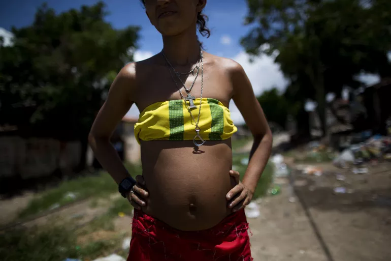 foto mostra a barriga de uma adolescente gr&aacute;vida. seu rosto est&aacute; na sombra para proteger sua identidade