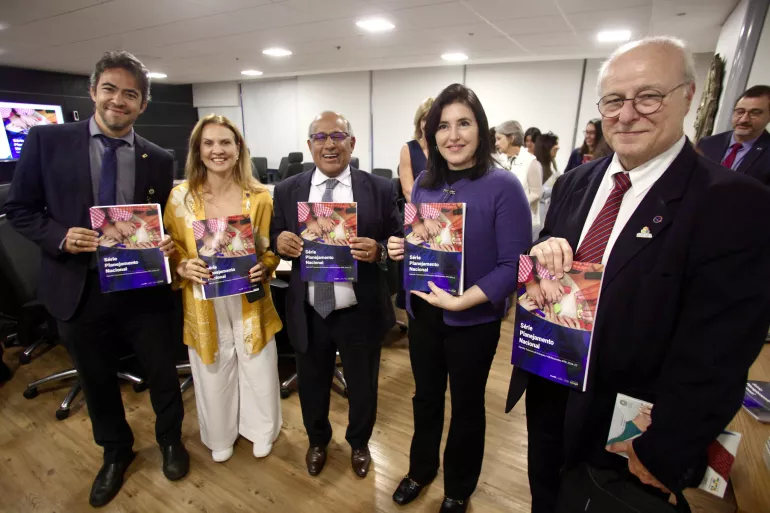 Grupo de pessoas em p&eacute; posando para foto segura publica&ccedil;&atilde;o nas m&atilde;os