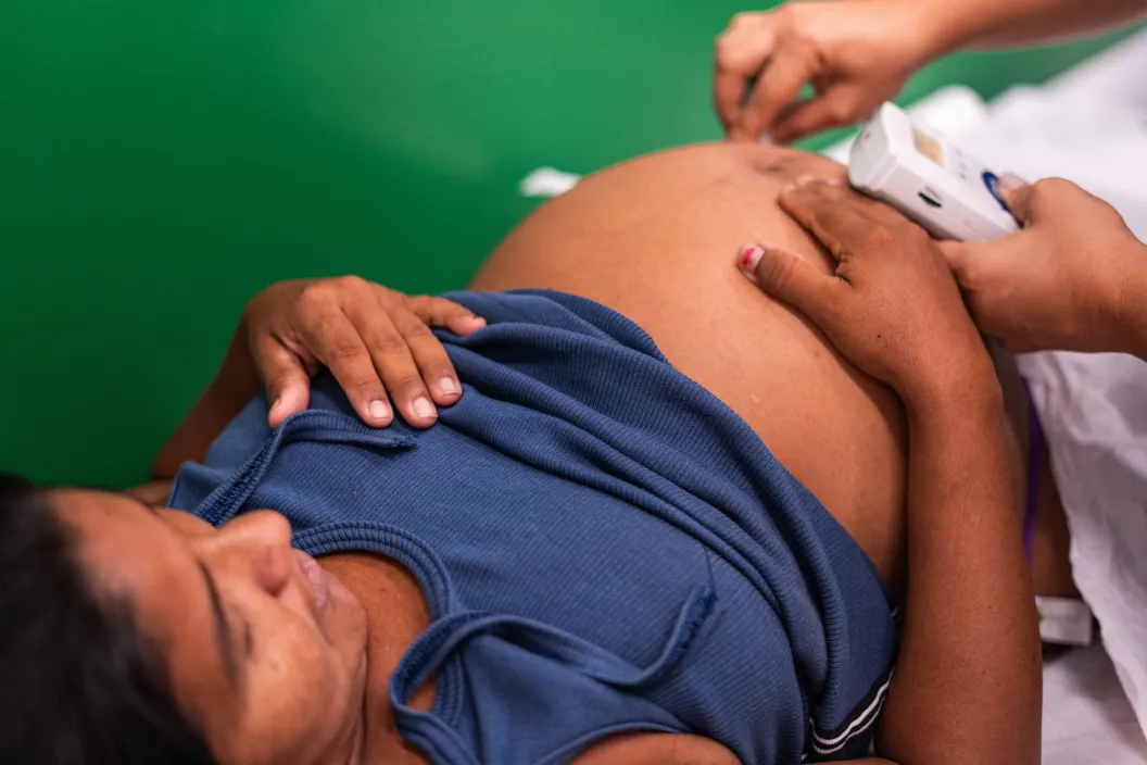 mulher gr&aacute;vida deitada sendo examinada por uma enfermeira