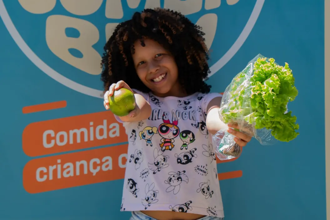 menina segura fruta e p&eacute; de alface