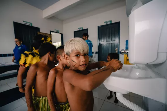 Meninos ind&iacute;genas em fila para lavar as m&atilde;os