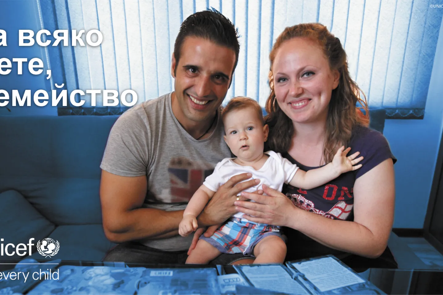 Майка и баща са прегърнали дете. Виски са щастливи и гледат към камерата. 