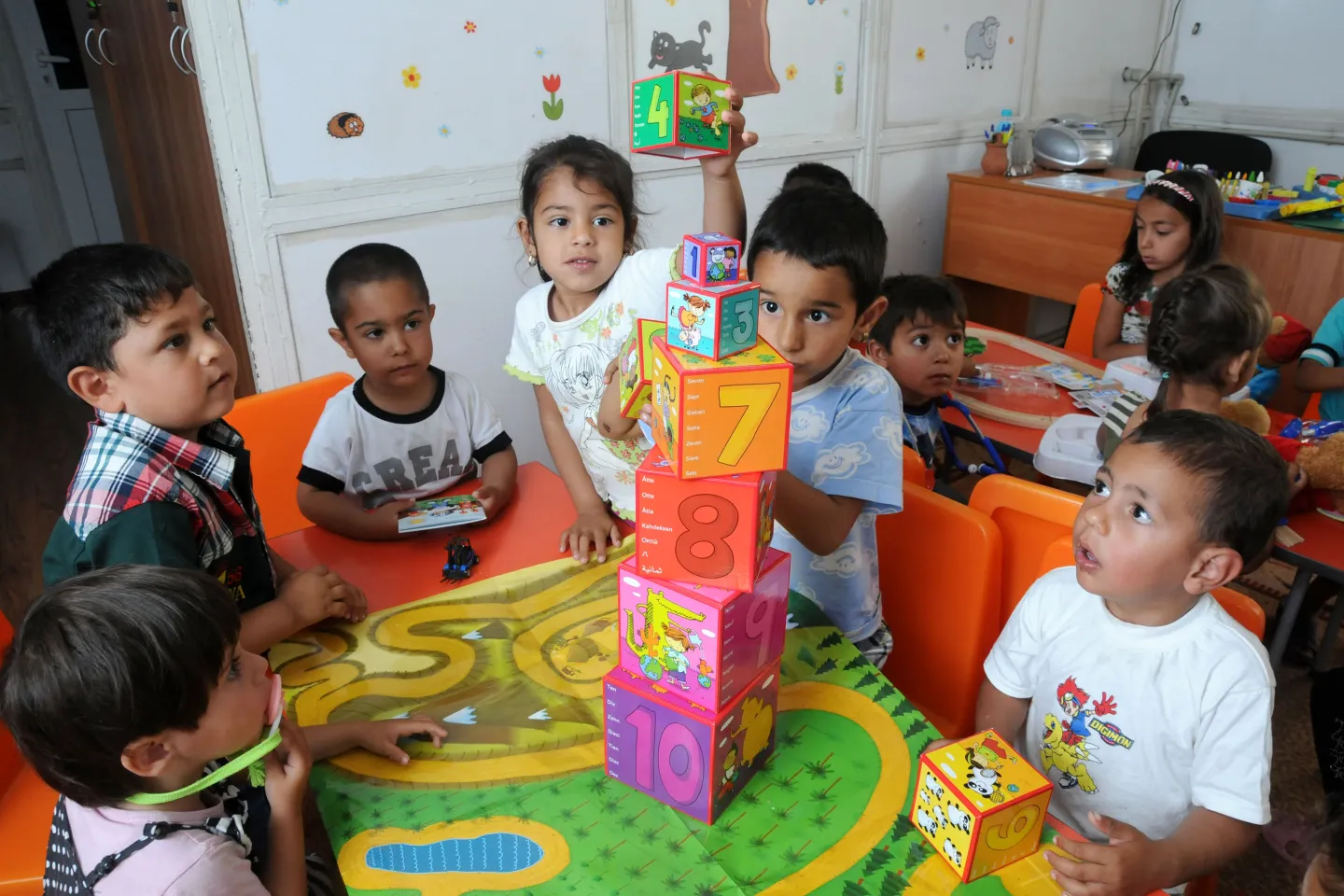 Children learning and playing at the kindergarten. They are building a tower of cubes