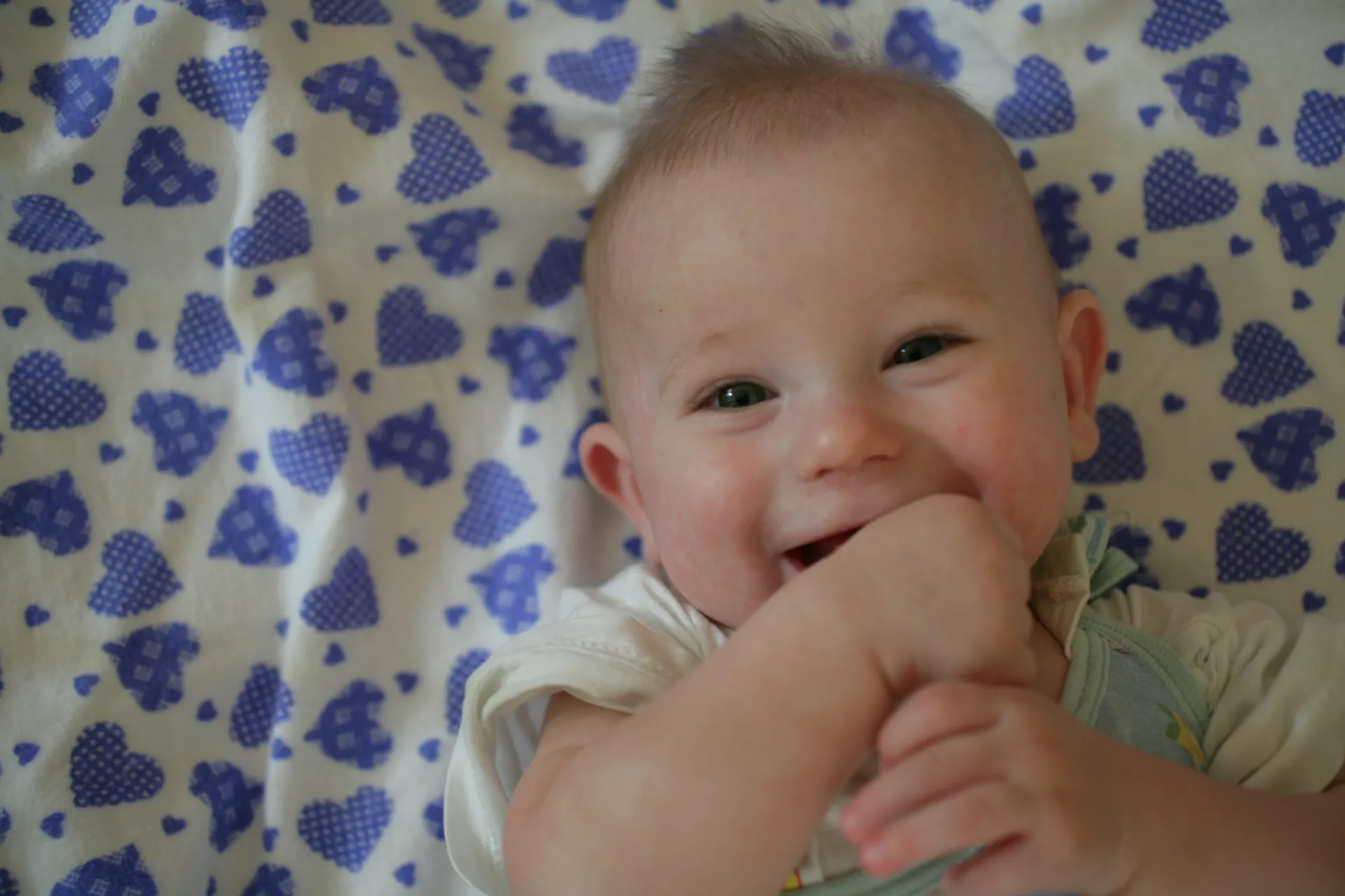 a few months old baby is smiling with hands in his or her mouth