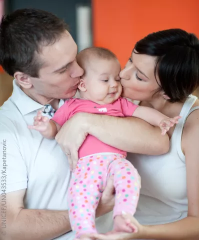 Майка и баща целуват детето си